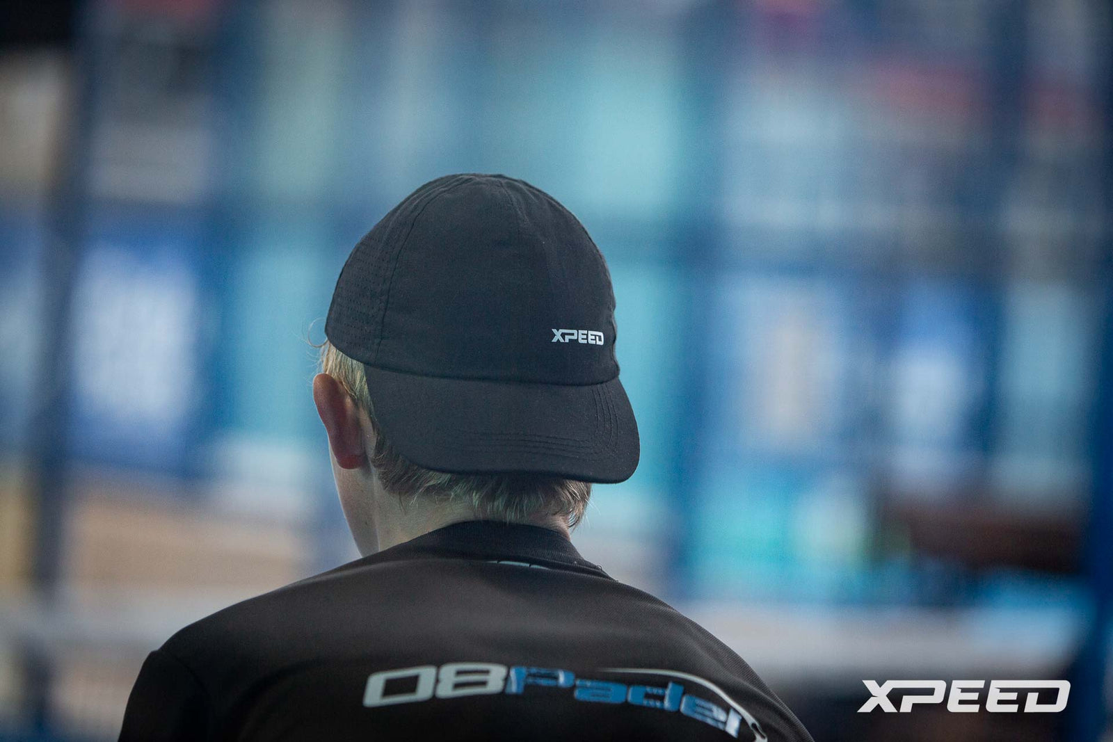 Jugador con gorra Xpeed siguiendo un partido de pádel